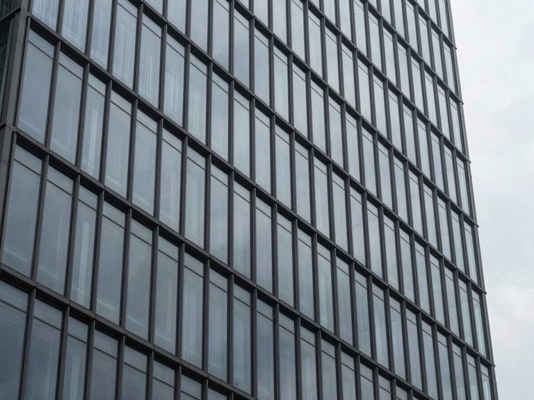 Close-up of a modern high-rise glazed facade reflecting an overcast sky, sharp architectural lines, desaturated steel and charcoal tones.