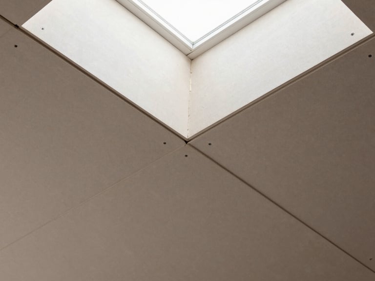 Overhead detail shot of gypsum board ceiling panels joined at seams, screws countersunk at regular intervals, joint compound applied at seams, natural daylight from a north-facing skylight creating even shadowless exposure, no people, tile pattern fills the frame edge to edge