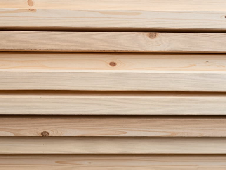 Overhead flat-lay of kiln-dried alder planks arranged in a tight bundle, close detail showing pale grain and smooth surface finish, even neutral daylight rendering colour and texture accurately, no people