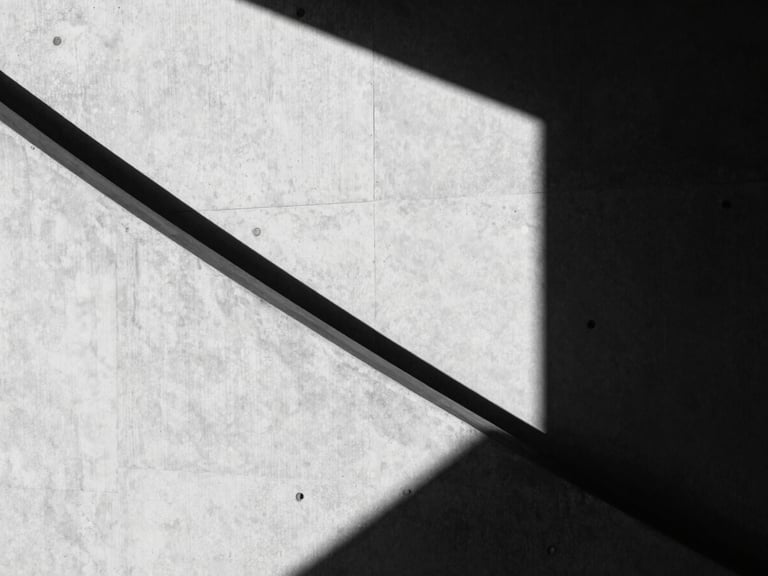 High-contrast black and white photography, sharp geometric shadows on a concrete wall, minimalist architectural line, 35mm lens