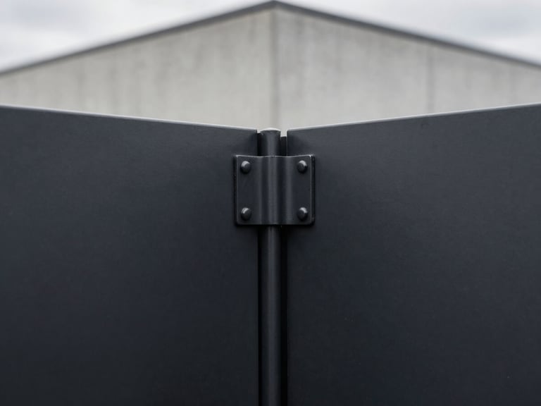 Macro detail of a clean seamless steel gate joint, perfect corner alignment, matte black finish, soft overcast light, desaturated industrial tones, 35mm lens