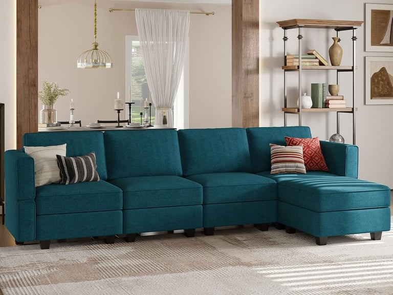 Modern teal blue sectional sofa with chaise lounge and throw pillows in a cozy living room.