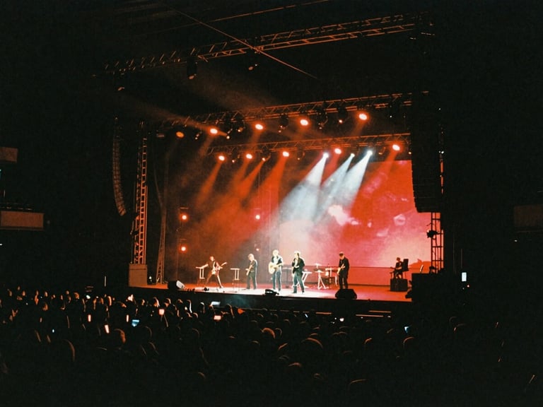 Cinematic film photography, dramatic high-contrast chiaroscuro lighting on a massive live event stage set, deep shadows with rich neon-red accents, anamorphic lens, 35mm