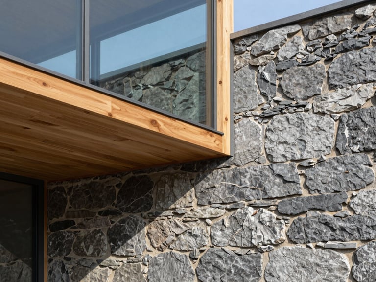 Architectural detail of a modern glass-and-timber joinery seamlessly meeting an original 19th-century granite foundation wall.