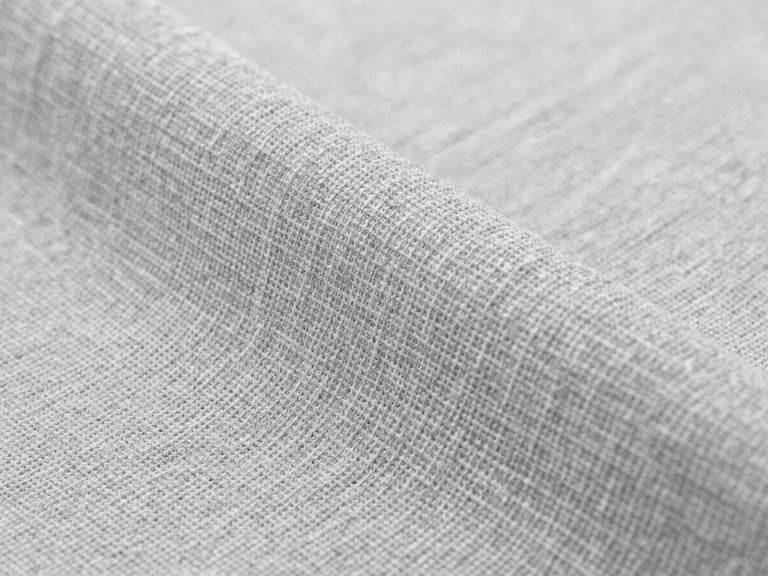 Macro close-up of premium slate gray organic cotton textile weave, bright neutral studio light, detailed fabric textures, sharp focus, high-end feel