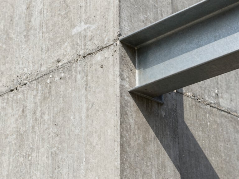 Close-up of raw board-formed concrete texture meeting a clean steel beam, hard natural light highlighting the structural grain.