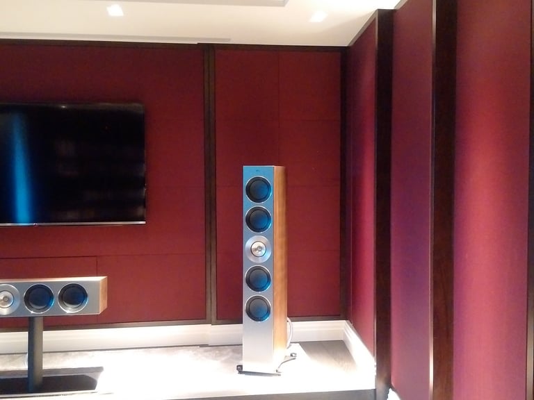 Red fabric wall finish in a residential media room with TV and speakers