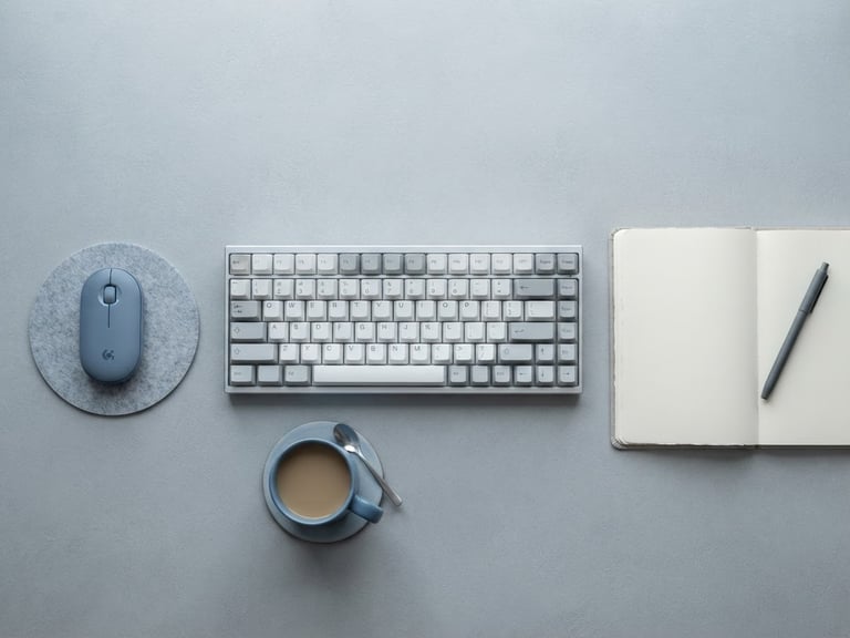 Top-down clean flat lay of a minimalist desk setup with a sleek keyboard and an empty notebook, soft cool daylight, cool gray and muted blue tones, macro lens