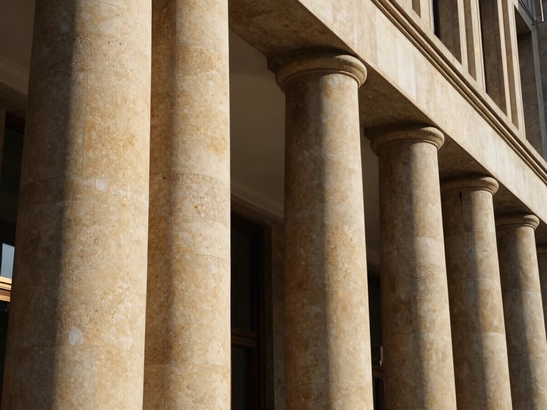 Macro architectural photograph of curved hotel lobby columns wrapped in warm sand travertine flexible stone, low-angle natural light, deep shadows