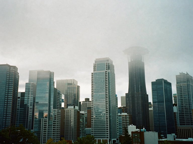 Wide environmental shot of the Seattle skyline shrouded in thick morning mist, modern glass skyscrapers reflecting cool blue-hour light, 35mm film.