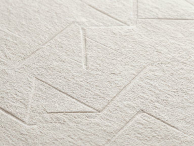Abstract macro photograph of heavy, textured cotton paper with a clean geometric blind debossing, professional and understatedly luxurious.