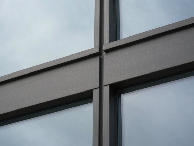 A close-up macro shot of brushed dark steel and structural glass panels, clean architectural grid, cold overcast daylight