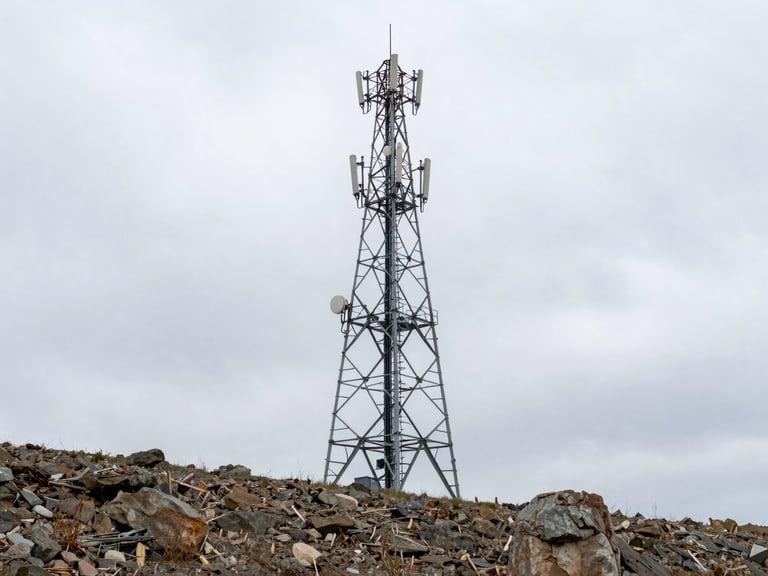 Wide environmental shot of a heavy-duty telecommunication tower on a rugged Ukrainian hillside under cold overcast daylight, desaturated steel tones, sharp focus, 35mm lens.
