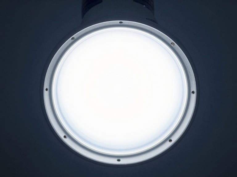 High-efficiency LED bulb, frosted diffuser, cool high-key laboratory light, sharp metallic textures