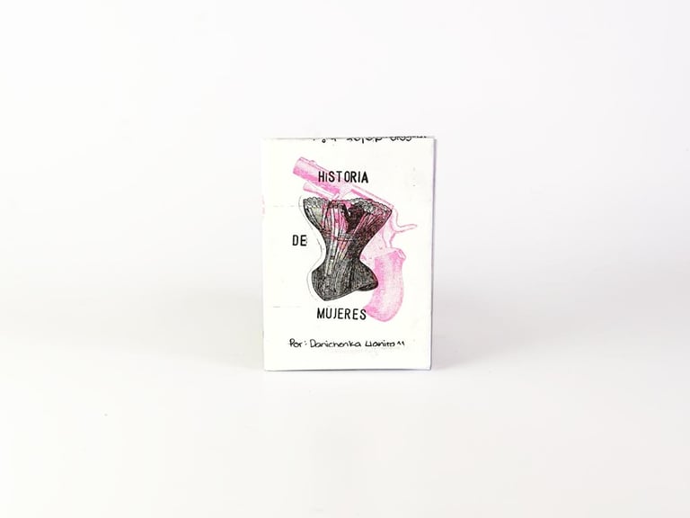 Fanzine artesanal titulado Historia de Mujeres con una ilustración de un corsé y un revólver rosa.
