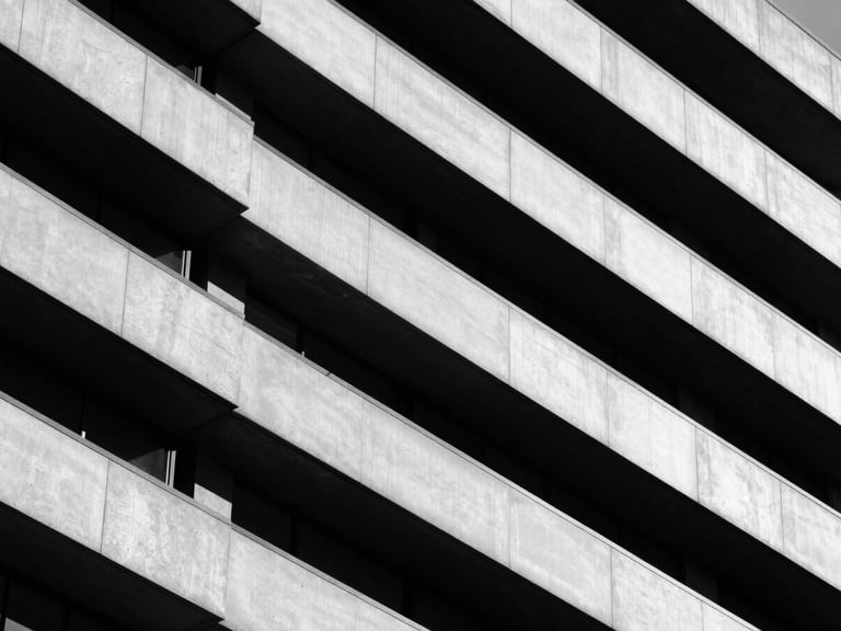 Architectural close-up of a modern corporate building facade, sharp diagonal shadows, high-contrast monochrome, minimalist