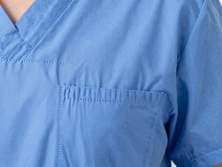 Macro shot of reinforced double-stitching on a medical scrub pocket, showing the tight, precise seams. Bright clinical studio light, sharp focus.