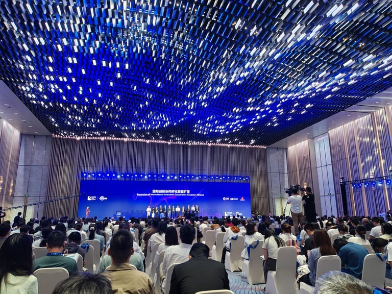 Audience at an international innovation conference under a blue light installation in a modern hall.