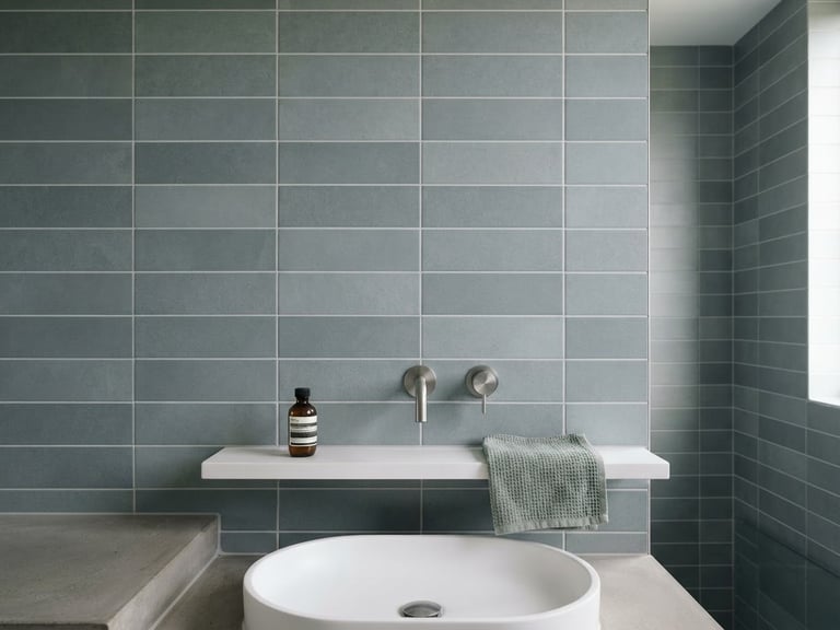 Straight-on architectural shot of a minimalist bathroom wall with perfectly aligned grey porcelain tiles and clean grout lines, bright natural daylight, sharp focus, 35mm