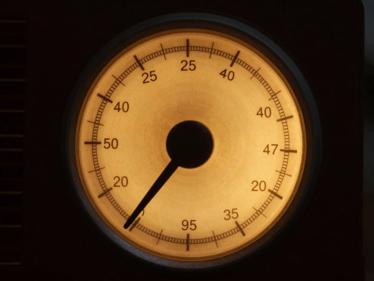 Close-up of a vintage analog radio dial with warm amber backlight illuminating frequency markings, deep shadow surrounds the dial face, warm tungsten glow, intimate and tactile