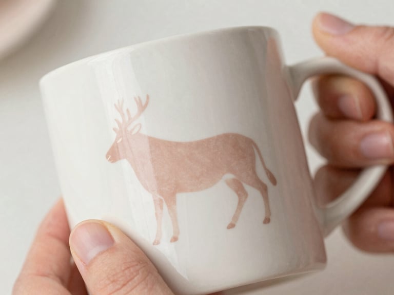 Close-up of a Scandinavian-inspired vinyl decal applied to a ceramic mug, hands smoothing out the vinyl, soft diffused daylight, matte finish.