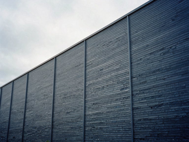 Industrial manufacturing facility exterior, metallic cladding, cool slate tones under overcast UK sky, clean architectural lines, 35mm