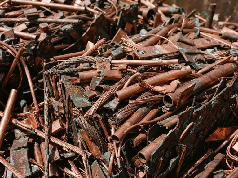 Macro shot of sorted copper scrap under harsh direct daylight, high-contrast metallic textures, sharp focus, 35mm.