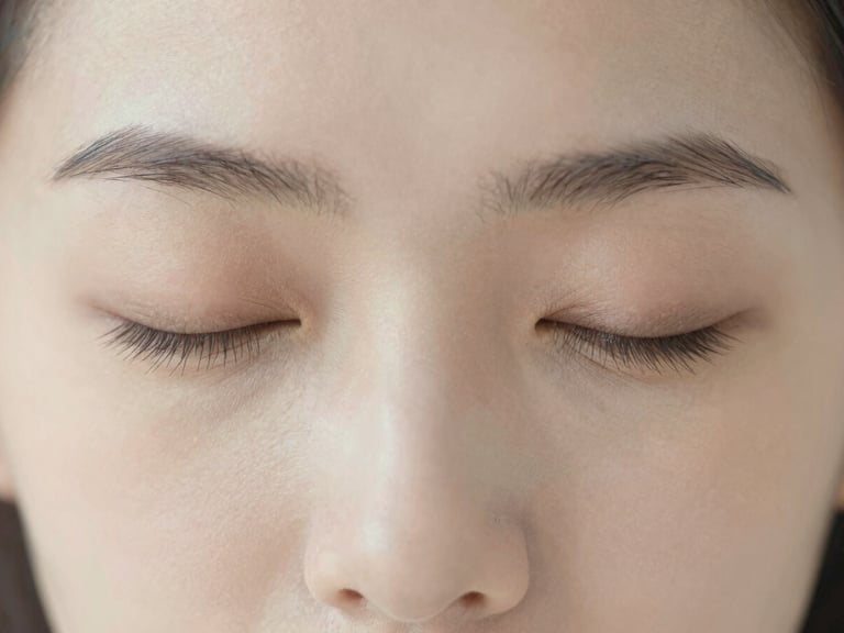 Close-up of a person's eyes closed in concentration, subtle lines of thought, soft light, serene expression, minimalist editorial photography.