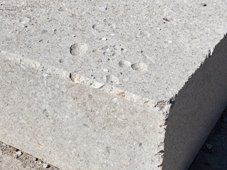 Close-up of raw textured limestone block being laid with millimeter precision, harsh natural side light highlighting the grain, gritty documentary photography, high contrast, 35mm
