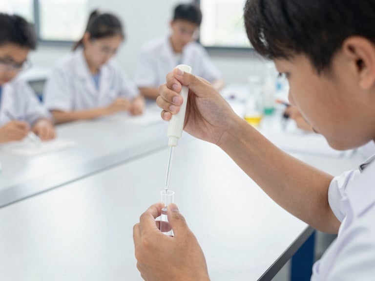 Close-up of a student in a diverse classroom setting, carefully pipetting a clear liquid into a small tube, bright natural classroom light, focused hands, 35mm lens.