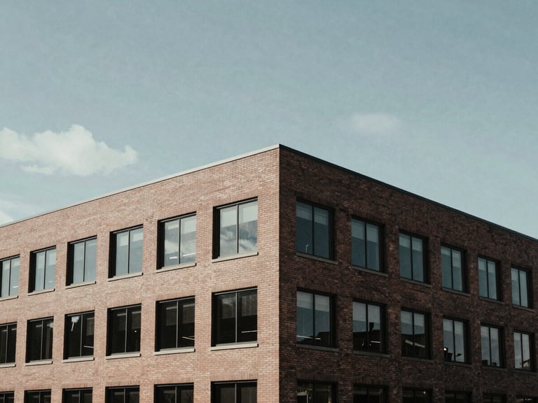 Architectural shot of a modern, low-profile brick office building in Alexandria under overcast daylight, clean lines, cinematic shadows.