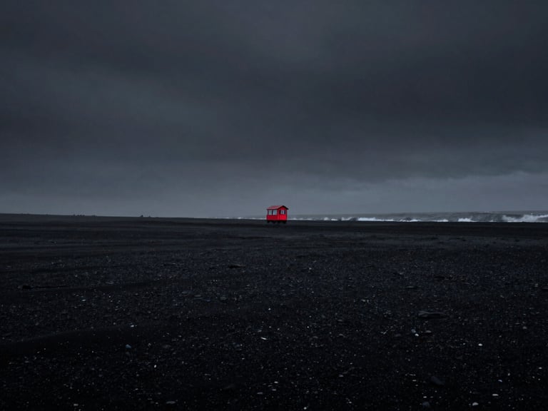 Desaturated black sand beach in Iceland under a dark heavy sky, low-key lighting, 35mm