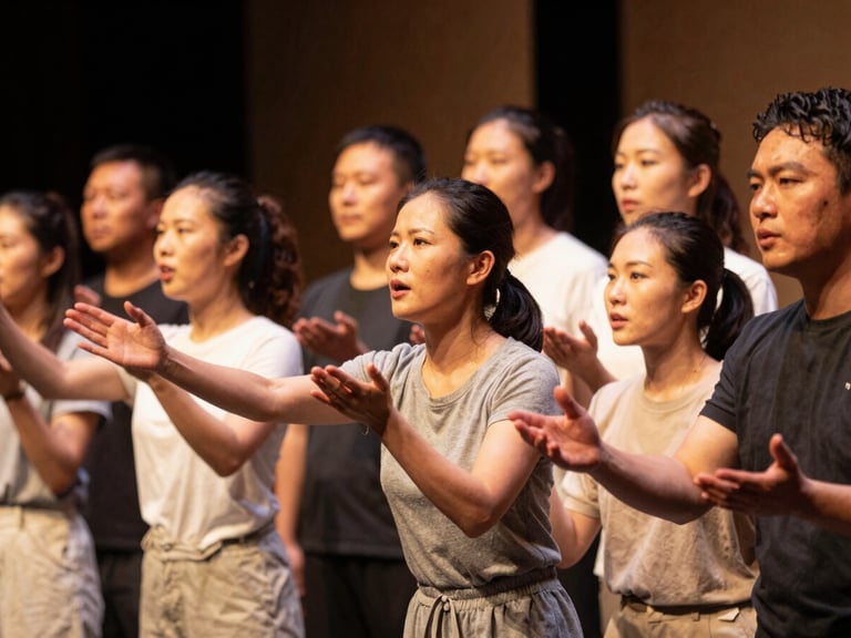 Warm editorial photography of an intergenerational group staging a theater performance, soft ambient amber stage lighting, expressive faces collaborating, shallow depth of field