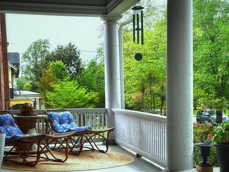 Front porch with lounger chairs and wind chimes 2123 Rivermont apartments