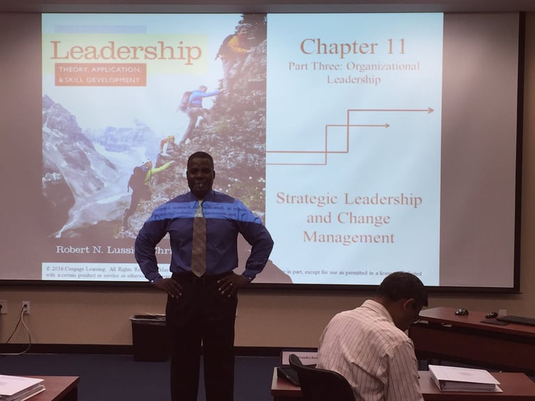 picture of Dr. Marlon standing in class in front of a projector screen with for a Leadership course