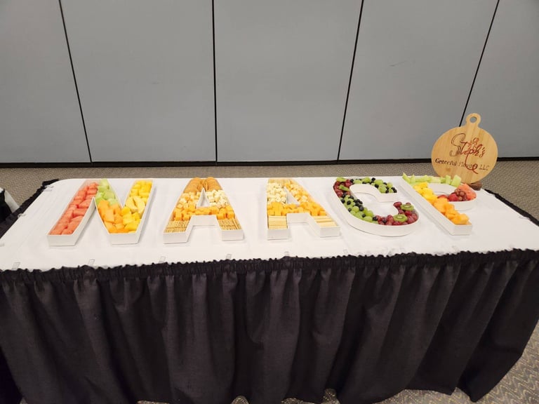 Fruit and cracker catering platter spelling NAACP in letter-shaped serving dishes on a table.