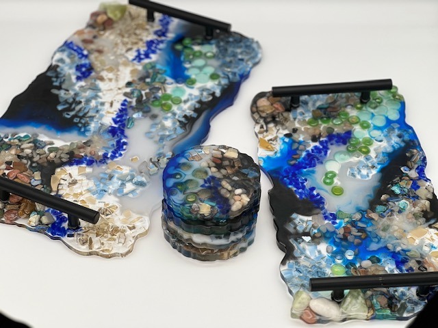 two trays with black handles, incorporating rock, shell, and glass design elements