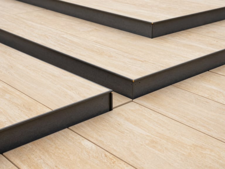 High-angle technical shot of a finished minimalist outdoor deck, sharp geometric lines, warm stone beige panels contrasting with charcoal gray metal framing, 35mm.