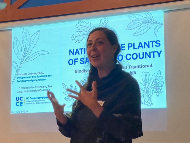 Woman speaking in front of a slide from UCANR