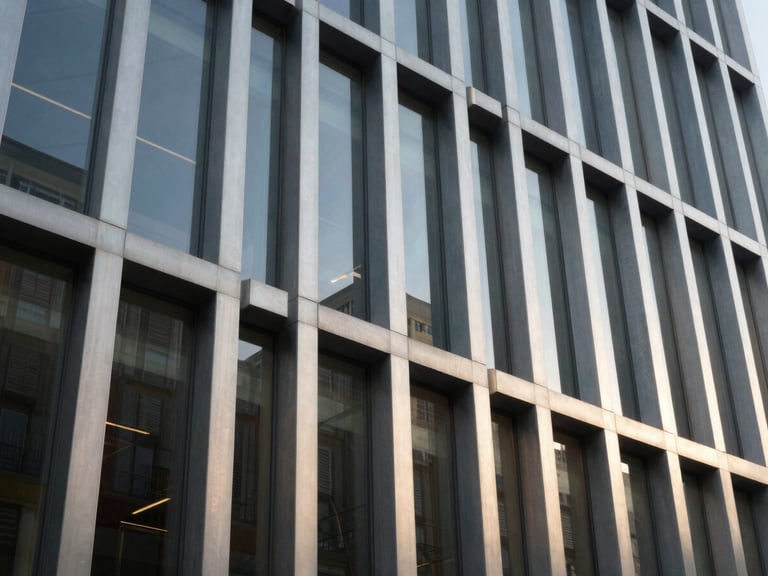Low-angle close-up of a modern architectural facade with structural glazing panels, crisp shadows, cool metallic daylight, sharp focus on joint details.