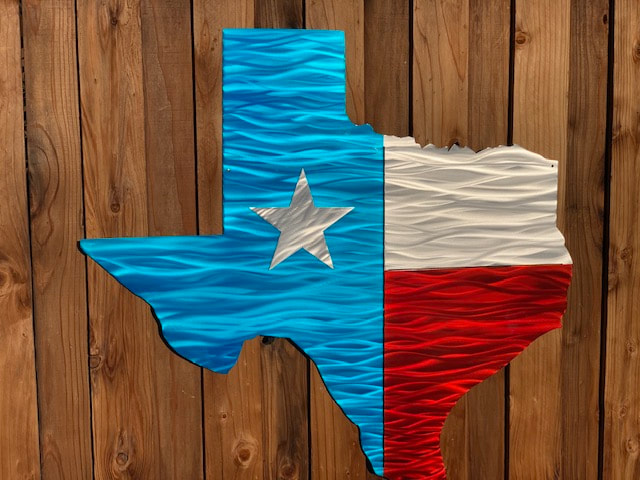 a texas flag shaped metal texas flag on a wooden fence