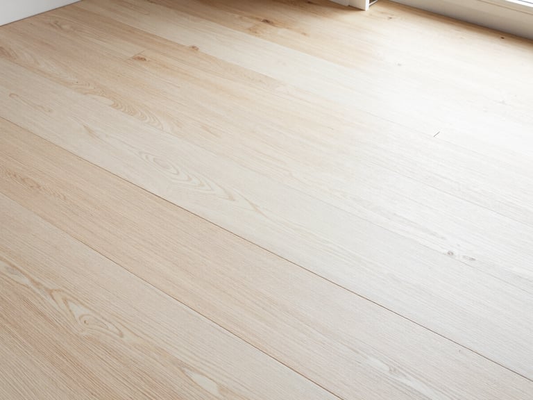 Overhead detail shot of interlocking natural white oak planks under bright Southern California window light, showcasing precise grain matching and minimal gaps.