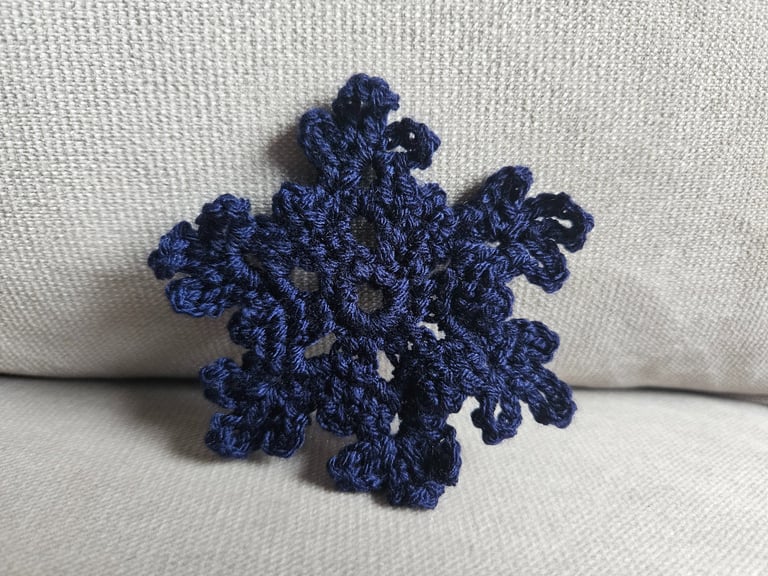 dark blue crochet snowflake on a light grey background