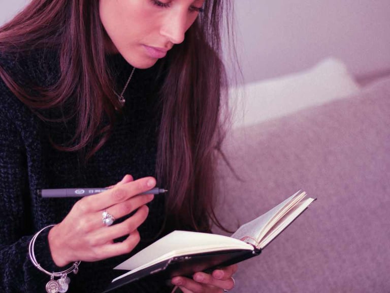 journaling lady in black knitted clothes with purple pen