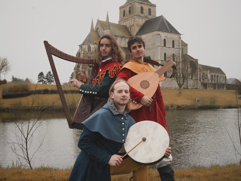 3 musiciens médiévaux devant une abbaye et un lac