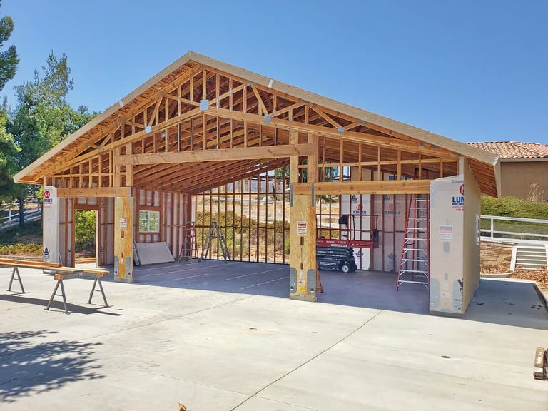 Large RV garage at framing stage with ladders and lift inside.