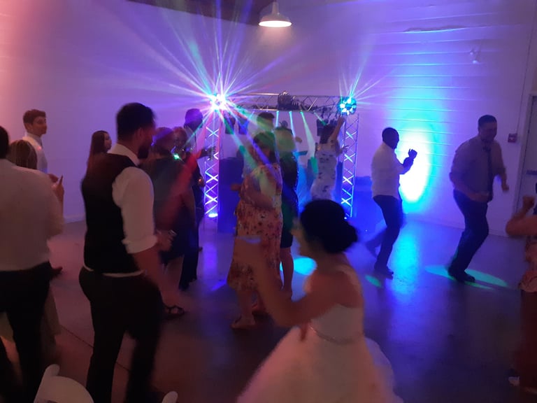 Wedding guests dancing in front of a DJ set-up with intense lighting