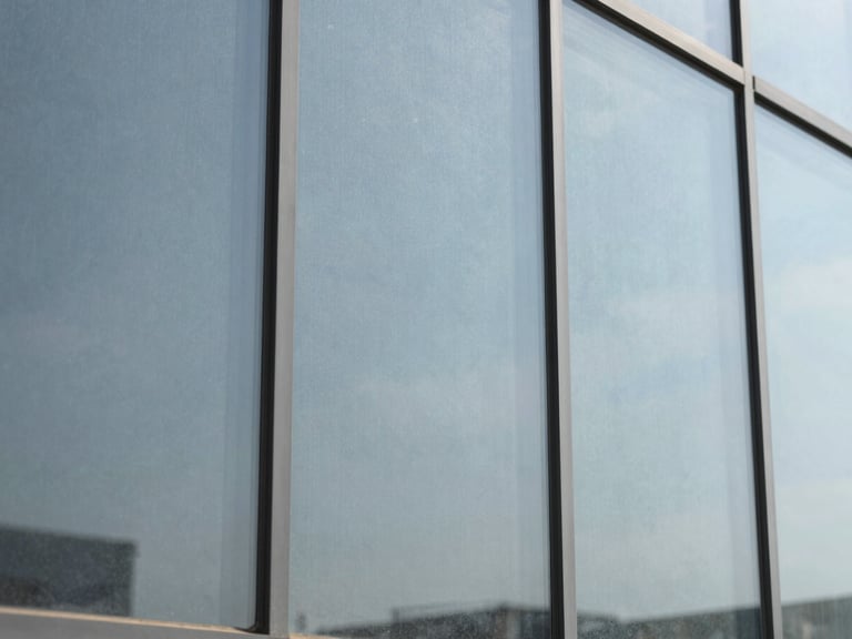 Close-up of a glass pane with a barely visible security film, showing slight reinforcement texture, cool tones, 35mm lens