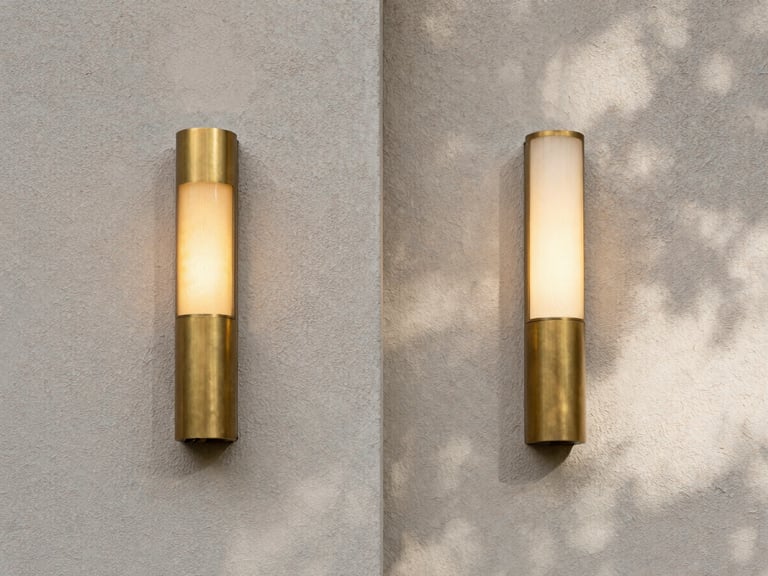 Symmetrical architectural composition, diffused natural daylight casting soft shadows on a textured plaster wall, matte brass fixture glowing softly to the left.