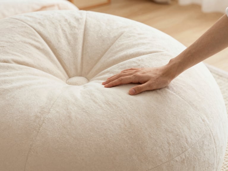 Close-up of a hand gently touching soft, patterned faux fur texture on a bean lounger, warm ambient light.